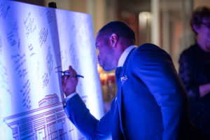 To commemorate the grand opening of an art building, guests signed a giant blueprint of the building as the departed.