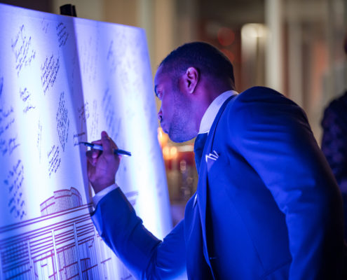 To commemorate the grand opening of an art building, guests signed a giant blueprint of the building as the departed.