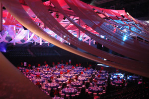 This arena was transformed into an elegant event with an intricate ceiling draping scheme and dynamic lighting that shifted through the evening for a corporate centennial celebration.
