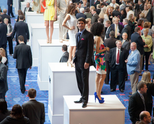 Models showcasing the new spring line atop of large pedestals during a networking reception were a unique sponsor benefit for this fashion retailer at a corporate event.